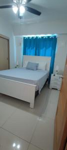 1 dormitorio con cama blanca y cortina azul en Boca del Mar Residence, Boca Chica en Boca Chica