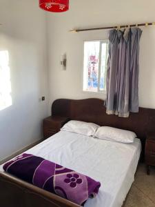 a bedroom with a bed with a purple blanket on it at Oceana surf house in Imsouane
