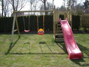 een speeltuin met een glijbaan en een schommel bij Ferienhaus in Rathjensdorf mit Grill, Garten und Terrasse in Kronprinzenkoog