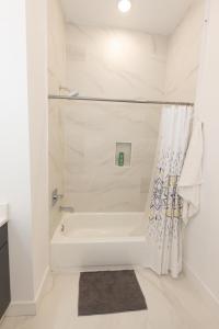 a white bathroom with a tub and a shower at Fully Furnished 2BR Gem mins to NYC in Bayonne