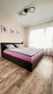 a bedroom with a large bed with a black frame at Apartament PURPLE in Poznań