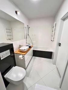 a bathroom with a toilet and a sink and a tub at Apartament PURPLE in Poznań