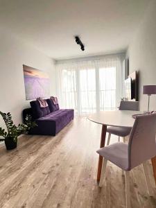 a living room with a purple couch and a table at Apartament PURPLE in Poznań