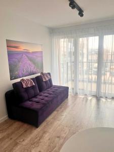 a living room with a purple couch in a room with windows at Apartament PURPLE in Poznań