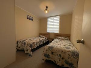 a bedroom with two beds and a window at Departamento Condominio Piscina in Villarrica +18 photos