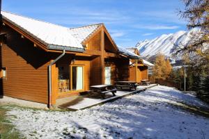 a log cabin in the snow with mountains in the background at Les Chalets Margot - Chalets pour 6 Personnes 651 in Le Dévoluy