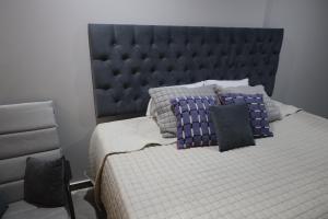 a bed with a blue headboard and pillows on it at Casa sabina aeropuerto plus 1 in Lima