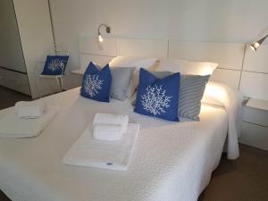 Una cama blanca con almohadas azules y toallas. en Lo Scalo 2.0, en Marina di Ragusa