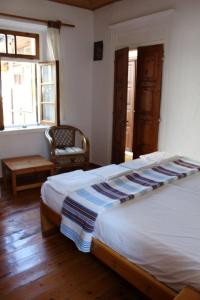 a bedroom with a bed and a chair and windows at Sotos pension in Skopelos Town