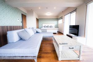 uma sala de estar com um sofá branco e uma televisão em Condominium Hotel Okinawa Yumeto - Vacation STAY 16527v em Nanjo