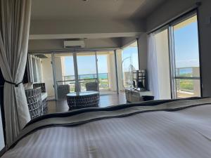 ein Schlafzimmer mit einem Bett und einem großen Fenster in der Unterkunft Condominium Hotel Okinawa Yumeto - Vacation STAY 16527v in Nanjō