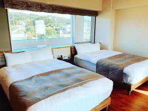 two beds in a room with a large window at Condominium Hotel Okinawa Yumeto - Vacation STAY 16578v in Nanjo