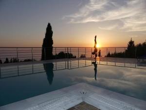 a woman standing next to a swimming pool at sunset at Studios Vrionis Panoramic Sunset in Kothréas