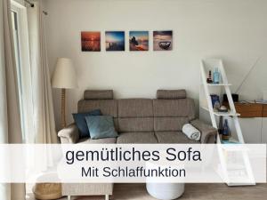 a living room with a couch and some pictures on the wall at Ferienwohnung Heimathafen Küstenwald in Gelbensande