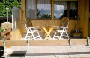 un par de sillas y una mesa en un porche en Ferienhaus Buchengrund mit eigenem beheizten Pool und Gegenstromanlage, en Sangerhausen