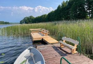 uma doca com bancos e um barco num lago em Dom nad jeziorem bania plaża bezpośredni dostęp do jeziora em Burbiski