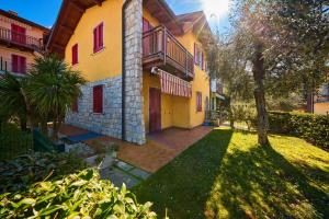 a large yellow building with red windows and a yard at A Casa di Anna Maria in Brenzone sul Garda