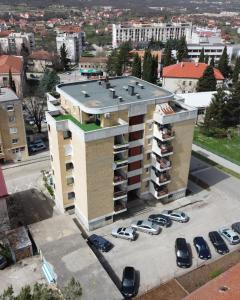 un gran edificio con coches estacionados en un estacionamiento en Sobe Zimmer Rooms 2, en Bileća