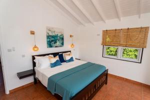 a bedroom with a bed and two windows at Hodges Bay House in Calibishie