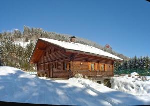 une cabane en rondins avec de la neige sur le toit dans l'établissement Holzblockhaus auf zwei Etagen mit Whirlbadewanne und Kaminofen, à Berg im Drautal