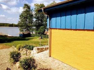 un edificio amarillo y azul junto a un lago en Feriengrundstück direkt am See, en Dabel