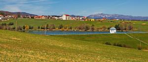 um campo verde com um lago e uma cidade em Ubytovanie v Kanianke em Kanianka