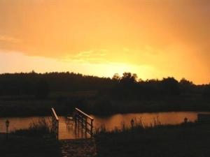 einen Sonnenuntergang über einem Wasserkörper mit einem Dock in der Unterkunft Ferienhaus für Naturliebhaber 