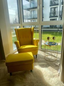 a yellow chair and a stool in a room with a window at Apartament Twój ZDRÓJ & SPA Dr Duda in Busko-Zdrój