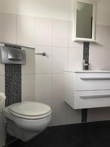 a white bathroom with a toilet and a mirror at Ferienwohnung in Wolfhagen mit Möbliertem Balkon in Wolfhagen