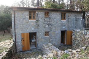 una casa in pietra con porte e finestre in legno di Ferienhaus in Ameglia mit Garten, gemeinsamem Pool und Grill a Monte Marcello