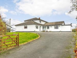 a white house with a fence and a driveway at 5 Bed in Mold 79345 in Llanferres