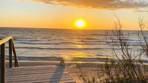 a sunset on the beach with a wooden pier at Grunwaldzka 12 B22 - Easy-Rent Apartments - 50m od plaży in Pobierowo +39 photos