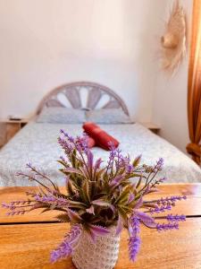 a vase with purple flowers on a table next to a bed at My home in Saint-Tropez