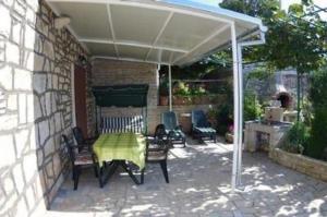 een patio met een tafel en stoelen onder een luifel bij Ferienhaus in Rakalj mit Grill, Garten und Terrasse in Rakalj