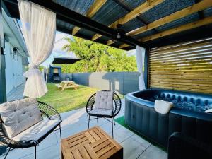 a hot tub on a patio with chairs and a table at Square Village in Capesterre-Belle-Eau