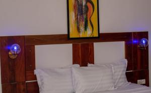 Bett mit einem Kopfteil aus Holz mit einem Gemälde darüber in der Unterkunft Hotel BKBG Benin in Cotonou