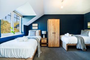 4 Bed Townhouse in Uxbridge Ideal For Families or Contractors في هيلينغدون: سريرين في غرفة بجدران زرقاء