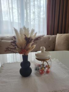 uma mesa com um frasco de vidro e um vaso com flores em Luxury apartment em Teteven