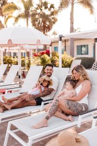 uma família sentada em espreguiçadeiras numa piscina em Postcard Inn On The Beach em St. Pete Beach