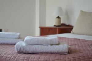 3 Handtücher werden auf einem Bett gestapelt in der Unterkunft Loupino Family House in Stoupa