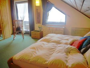 1 dormitorio con cama, ventana y silla en Geräumiges Apartment in einer idealen Lage mit eigenem Balkon und Blick auf die Berge en Sankt Michael im Lungau