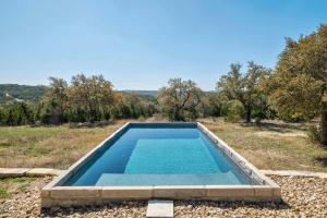 a swimming pool in the middle of a field at Hill Country Norwood House- 13 Acres, Private Pool and Pet Friendly! in Dripping Springs