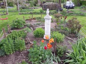 a garden with flowers and a statue in the middle at Appartement in Berlingen mit Garten, Terrasse und Grill in Berlingen