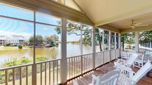 a screened porch with white chairs and a view of the water at Golf and Beach: 2BR Lakeside Villa with Lake Views in Pawleys Island