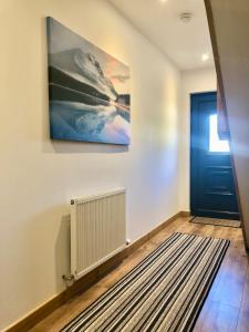 a hallway with a blue door and a painting on the wall at Brohar Annexe in Inverness