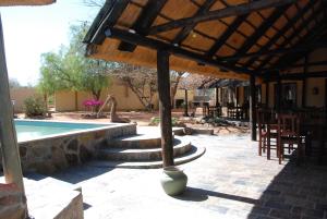 eine Terrasse mit einem Pool, einem Tisch und Stühlen in der Unterkunft Oppi-Koppi Rest Camp in Kamanjab