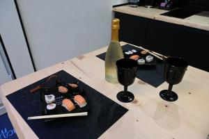 - une table avec deux assiettes de sushis et une bouteille de saké dans l'établissement DUCA DEGLI ABRUZZI Modern House LUXURY RELAX, à Brindisi