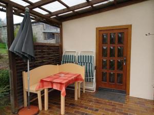 un patio con mesa, sillas y sombrilla en Kleines Ferienhaus in Garitz mit Garten, Terrasse und Grill, en Bad Kissingen