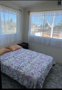 a bedroom with a bed and two windows at Casa rossi in Tecolutla