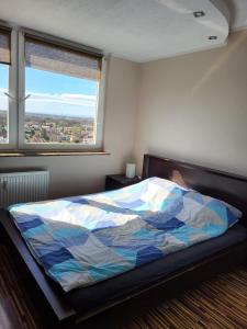 een slaapkamer met een bed met een kleurrijk dekbed en een raam bij Best View Wroclaw in Wrocław